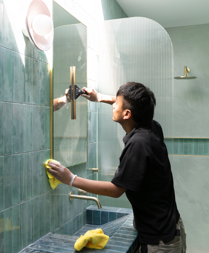 A person is cleaning a wall with a spray bottle and a cloth.