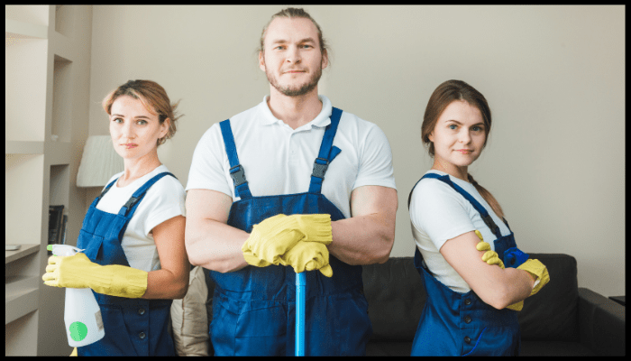 A man and two women are standing next to each other holding cleaning supplies.