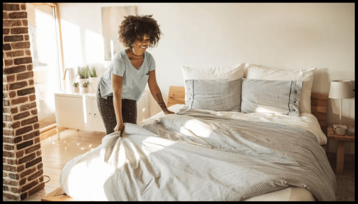 A woman is making a bed in a bedroom.