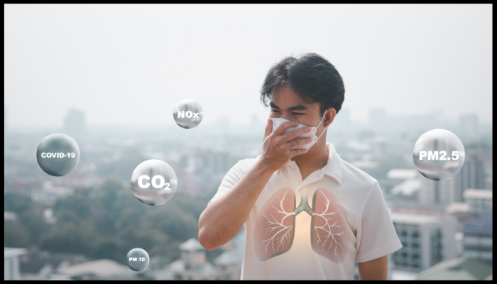 A man wearing a mask is coughing in front of a city skyline.