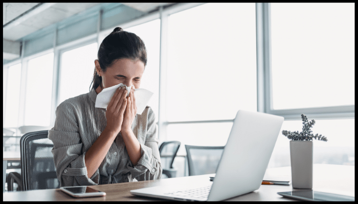 A man wearing a mask is coughing in front of a city skyline.