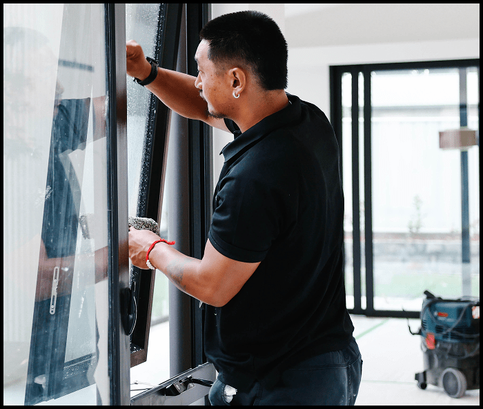 Cleaner wiping down large glass door as part of post construction cleaning process