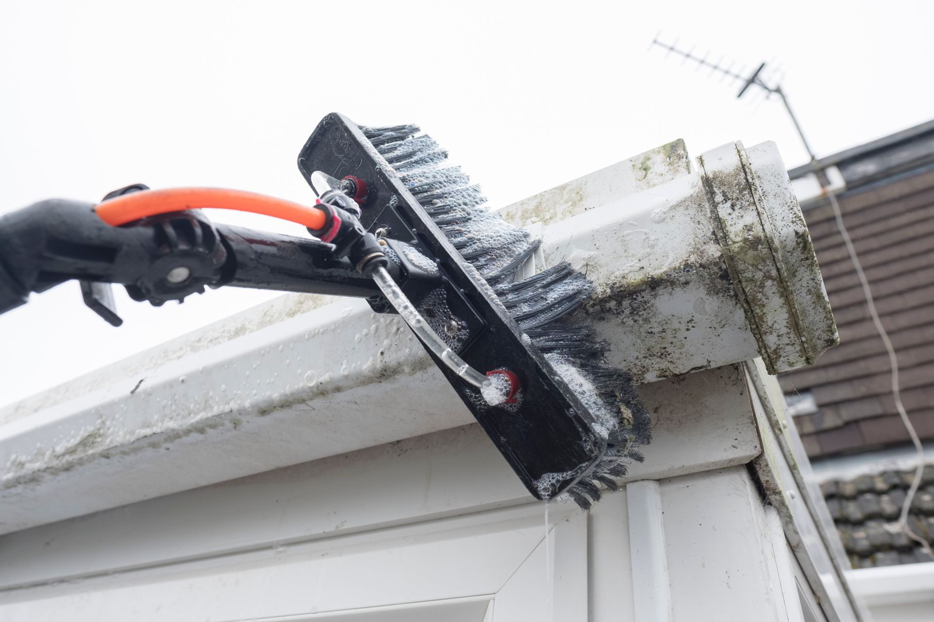 A person is cleaning a gutter with a brush.