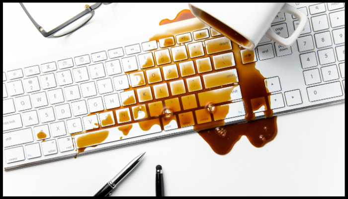 A cup of coffee spilled on a computer keyboard