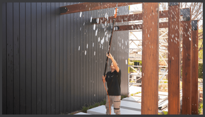 A person is cleaning a wall with a spray bottle and a cloth.