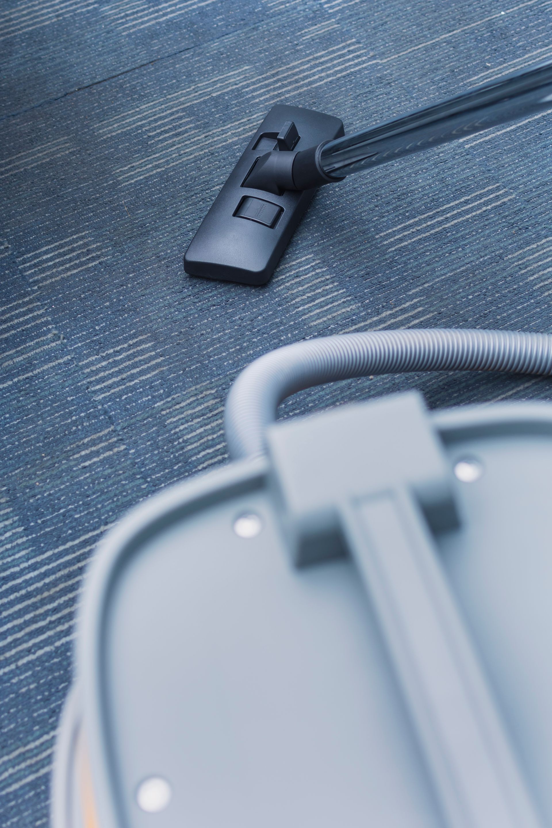 A vacuum cleaner is sitting on top of a blue carpet.