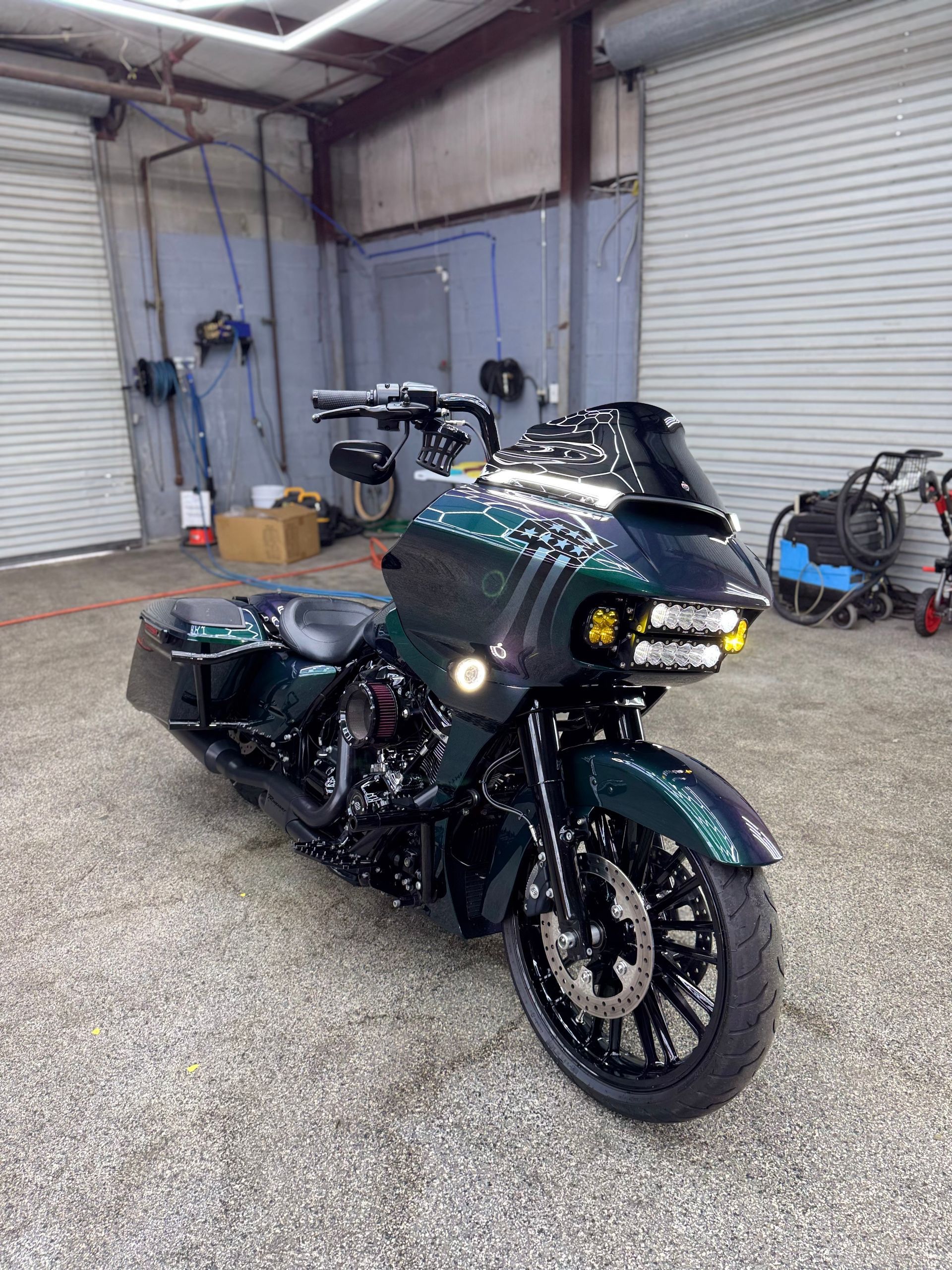 Dark green custom motorcycle with yellow headlights in a garage.
