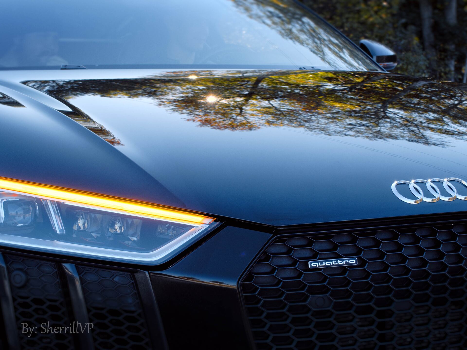 Person applying window tint to a car window with a yellow squeegee, inside a garage.
