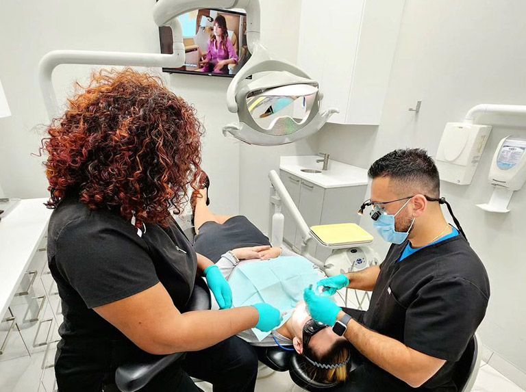 Dentist examining patient's teeth in a dental clinic, assistant present.