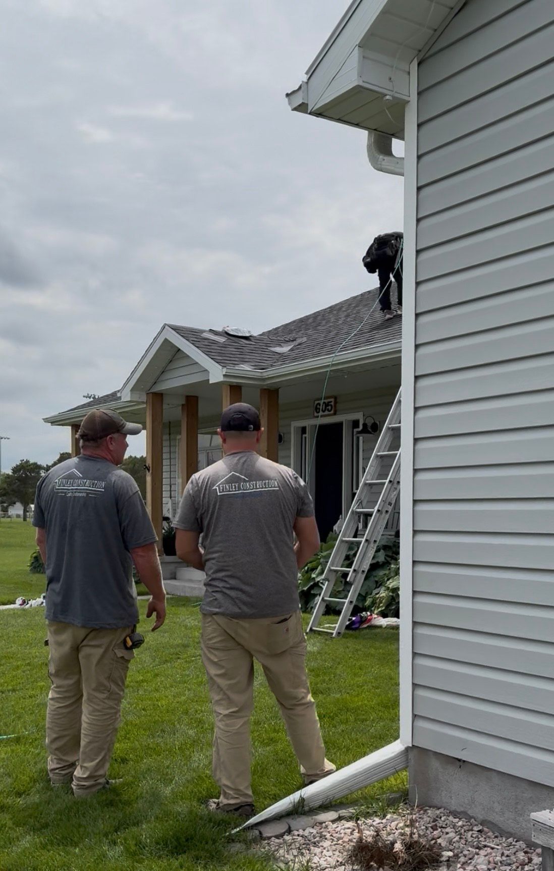 Two men are working on the roof of a house.