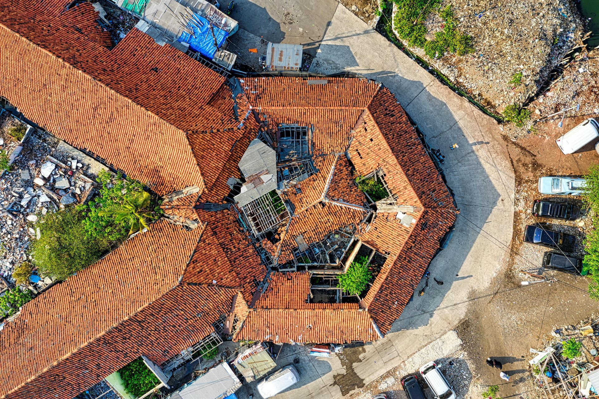 An aerial view of a building with a red tiled roof surrounded by trees.