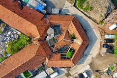 An aerial view of a building with a red tiled roof surrounded by trees.