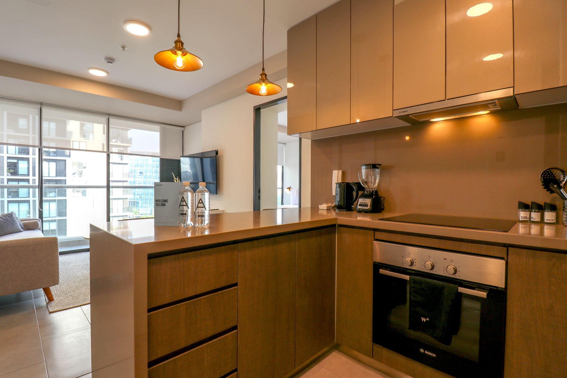 Una sala de estar con sofá, otomanas y cocina.