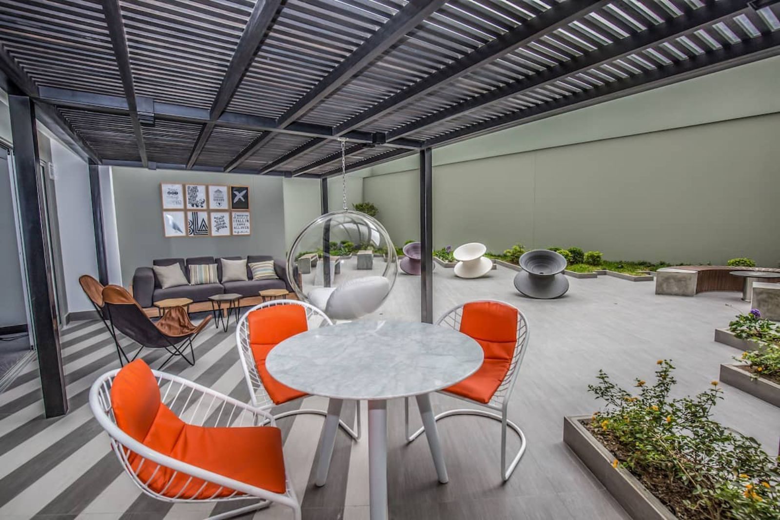 Un patio con mesa y sillas bajo una pérgola.