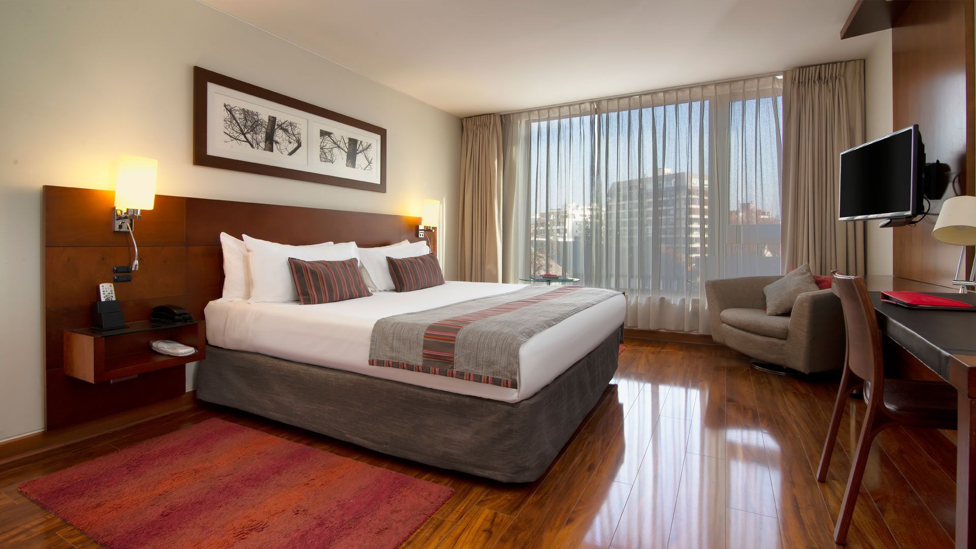 Una habitación de hotel con cama king size, silla, escritorio y televisión.