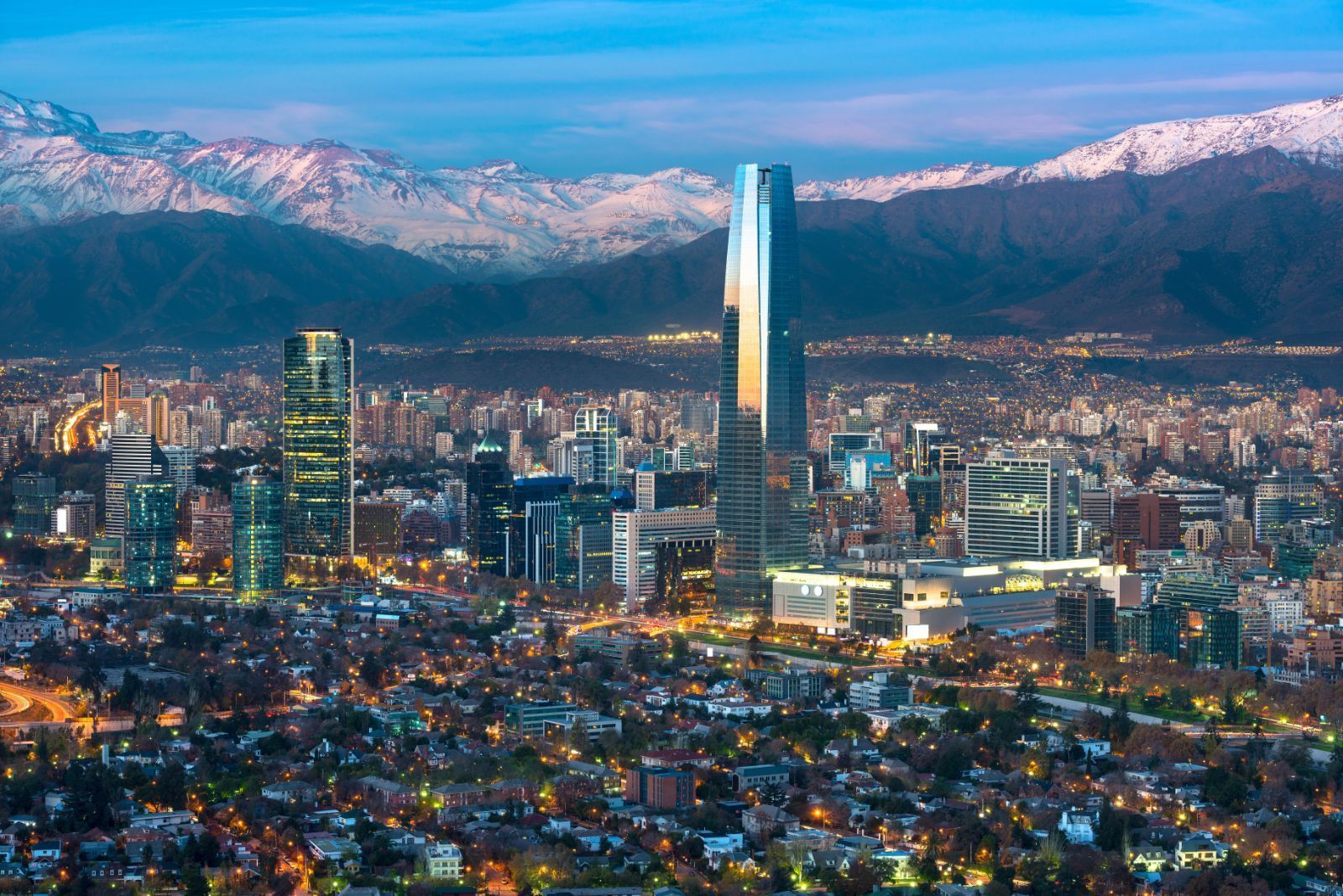 Una vista aérea de una ciudad de noche con montañas al fondo.