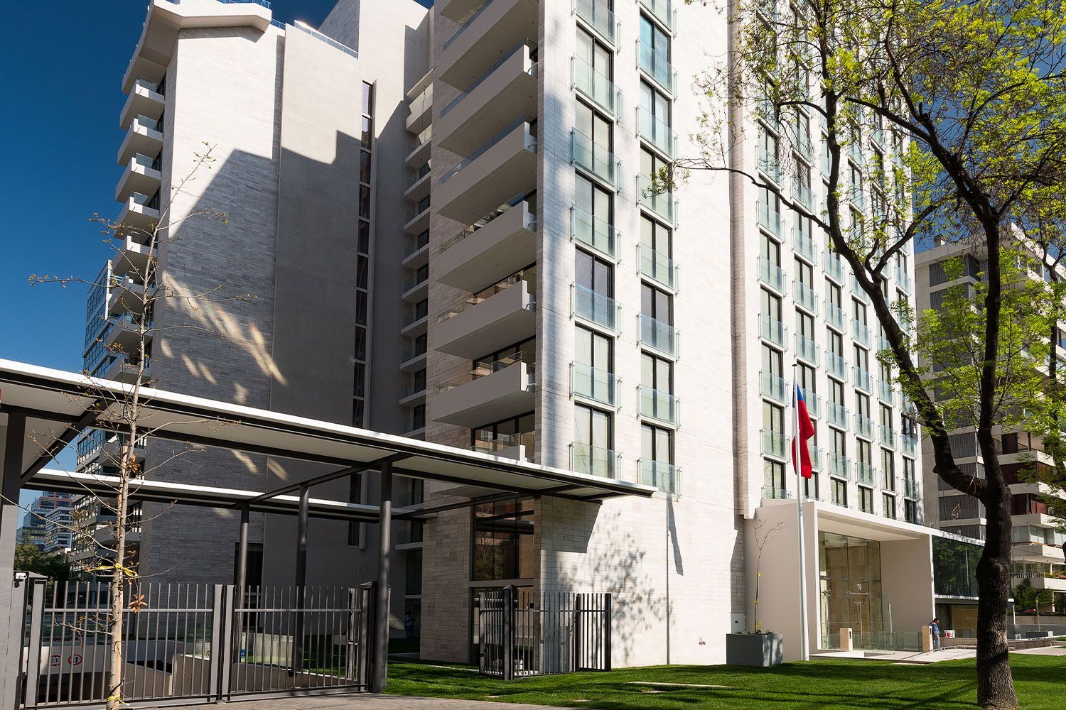 Un gran edificio blanco con muchas ventanas está rodeado de árboles y césped.
