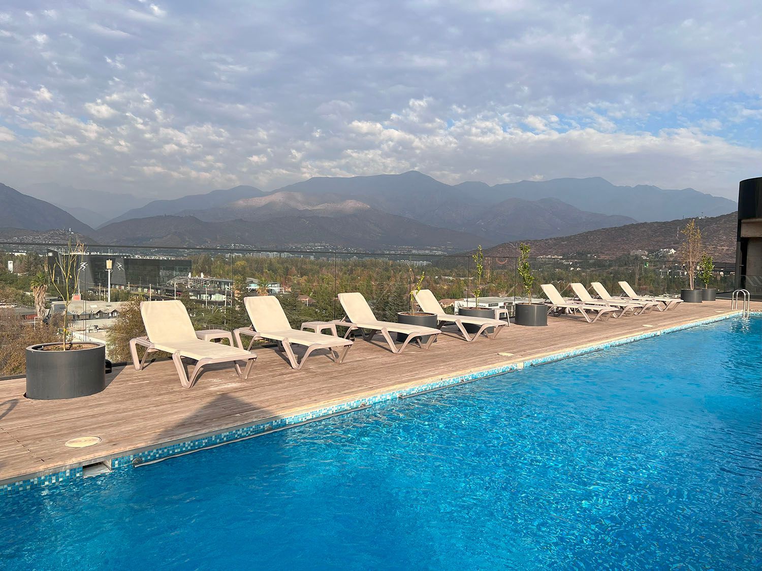 Una piscina con sillas y montañas al fondo.