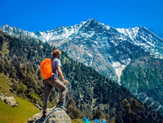 Trekking los Trapenses. Un hombre con una mochila naranja está parado en la cima de una montaña.