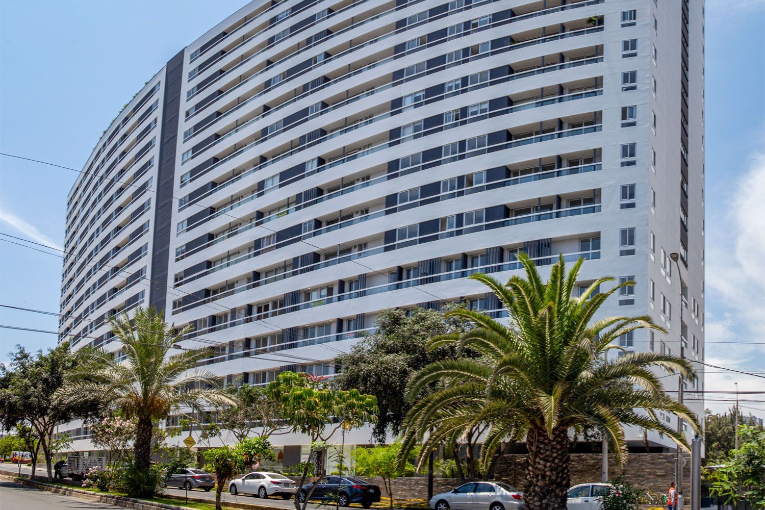 Un gran edificio con muchas ventanas está rodeado de palmeras.