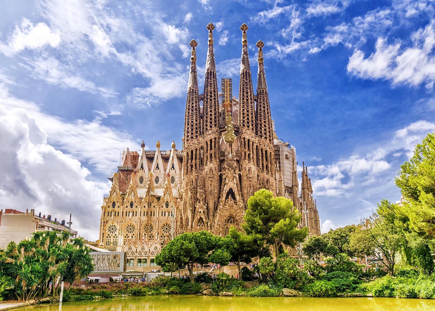 La catedral de la sagrada familia de barcelona está rodeada de árboles y un lago.