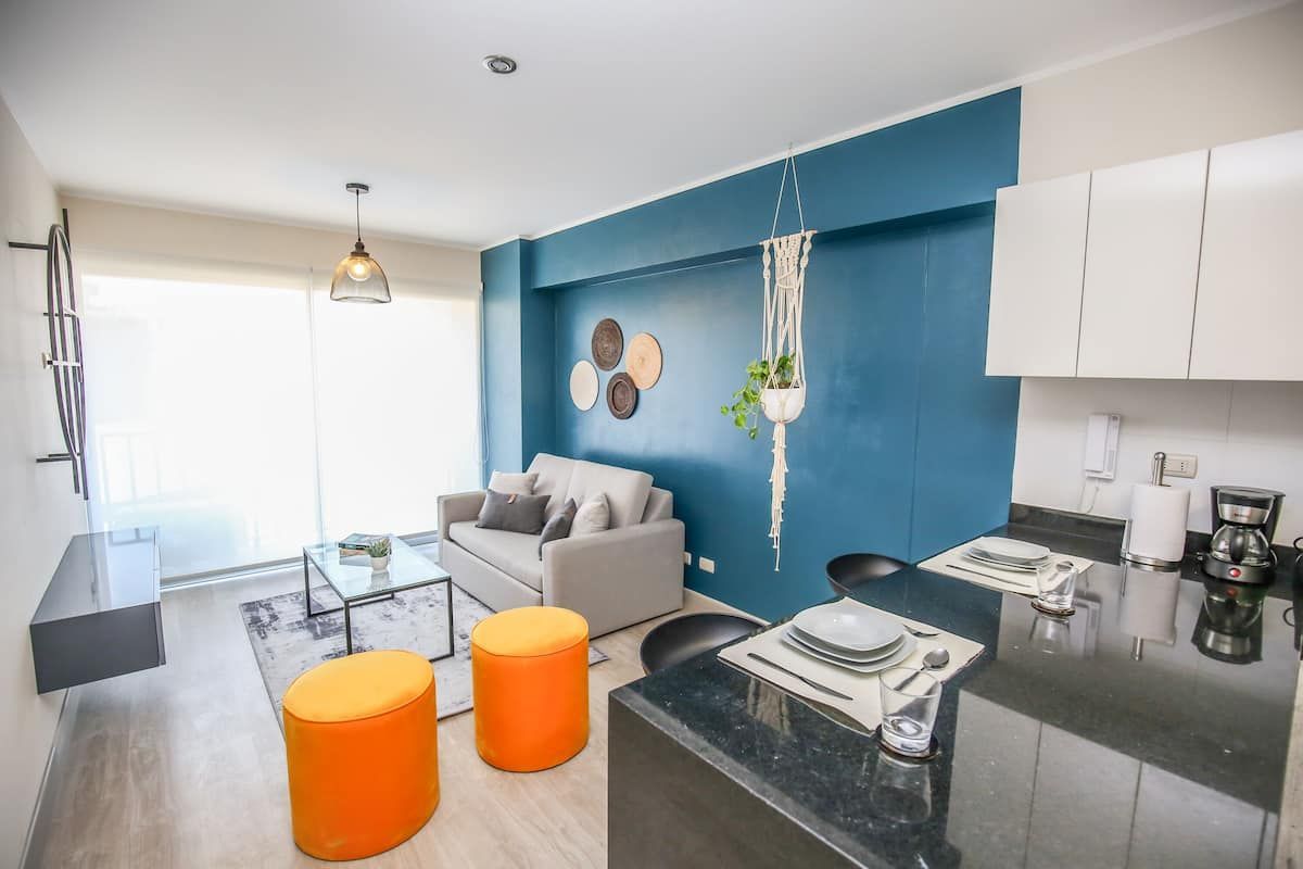 Una sala de estar con sofá, otomanas y cocina.