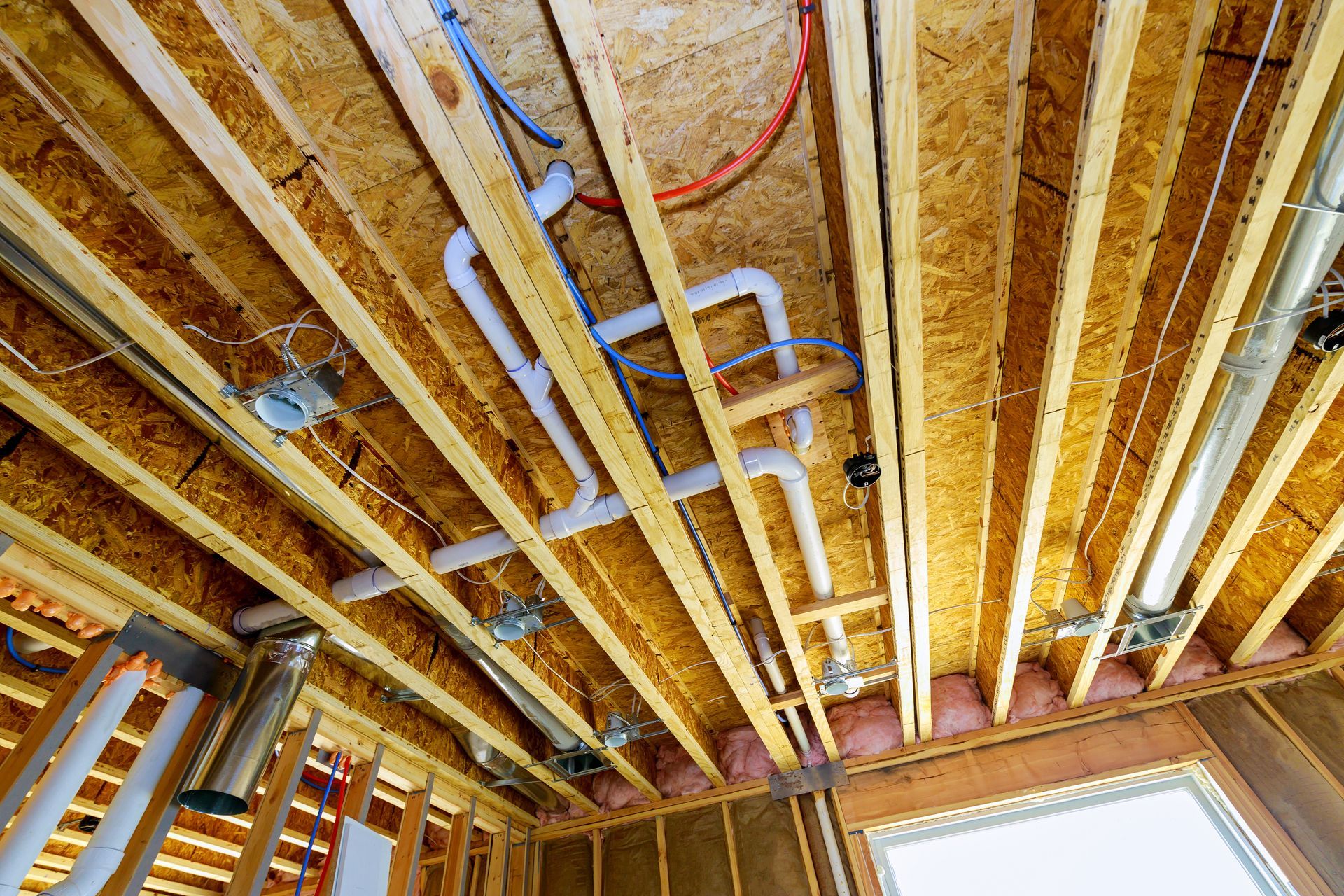 Woman in straw hat smiles, holding wine glass near a lake.