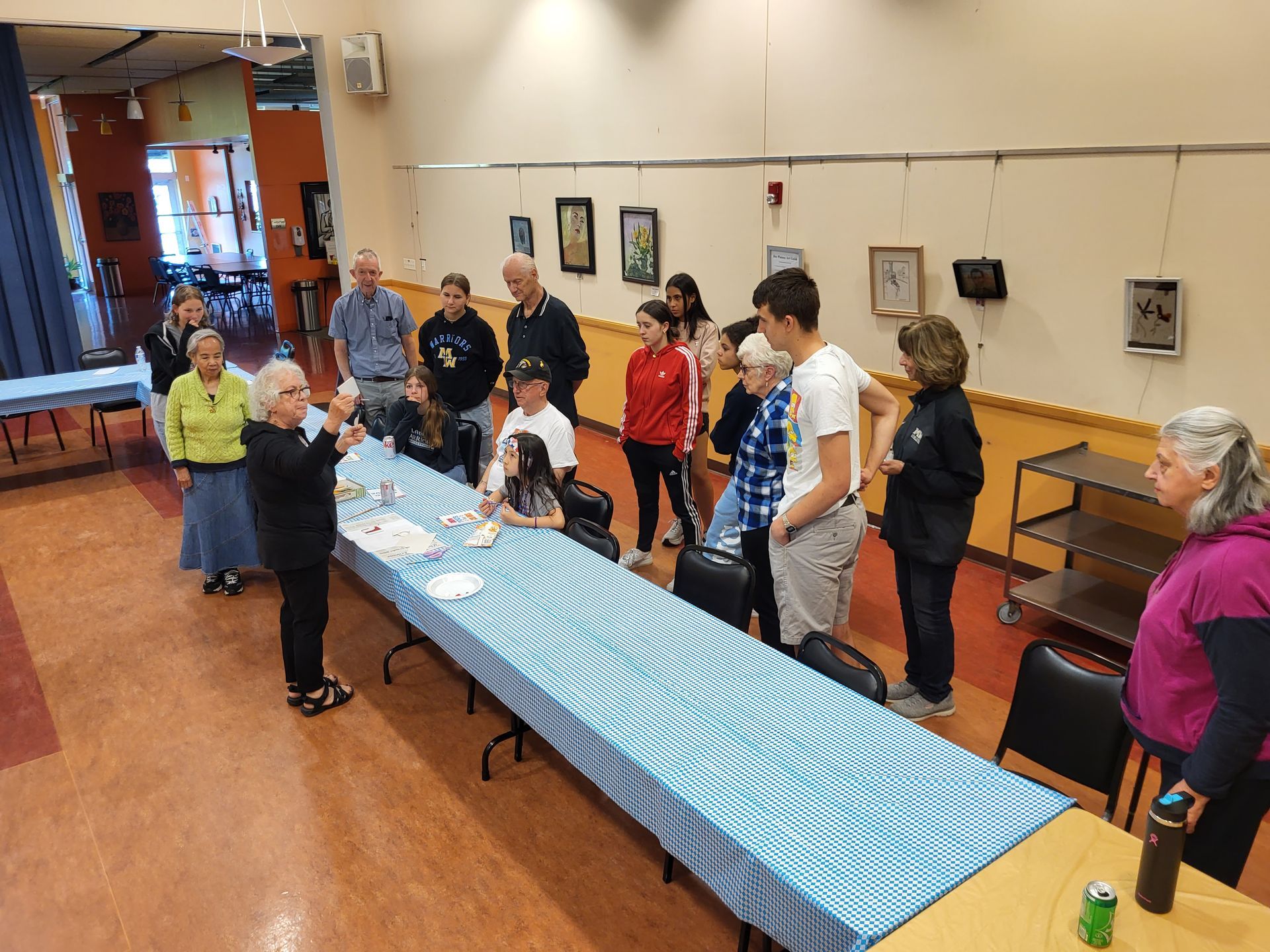 People gathered around a long table, listening to a speaker in a room with artwork on the walls.