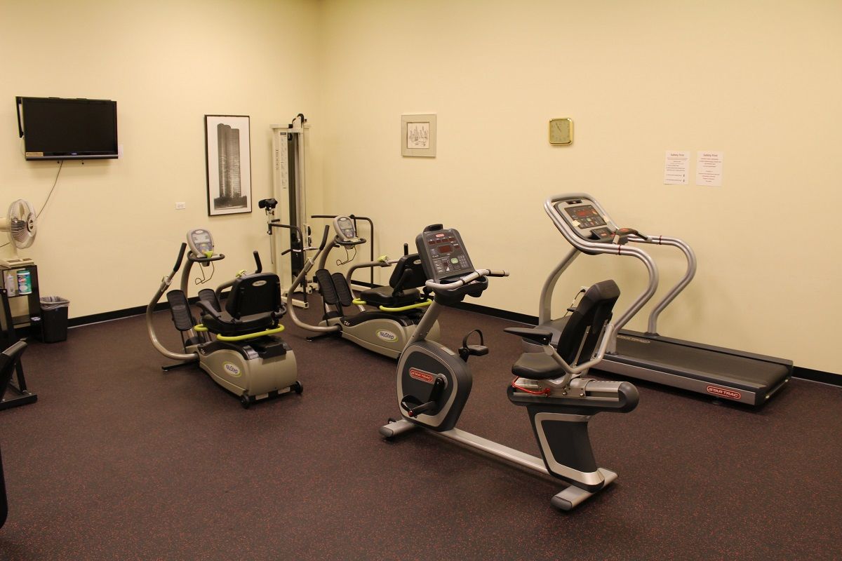 Gym with exercise equipment including treadmills and stationary bikes.