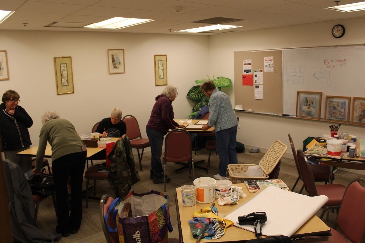 People working on art projects in a well-lit room with easels and artwork.