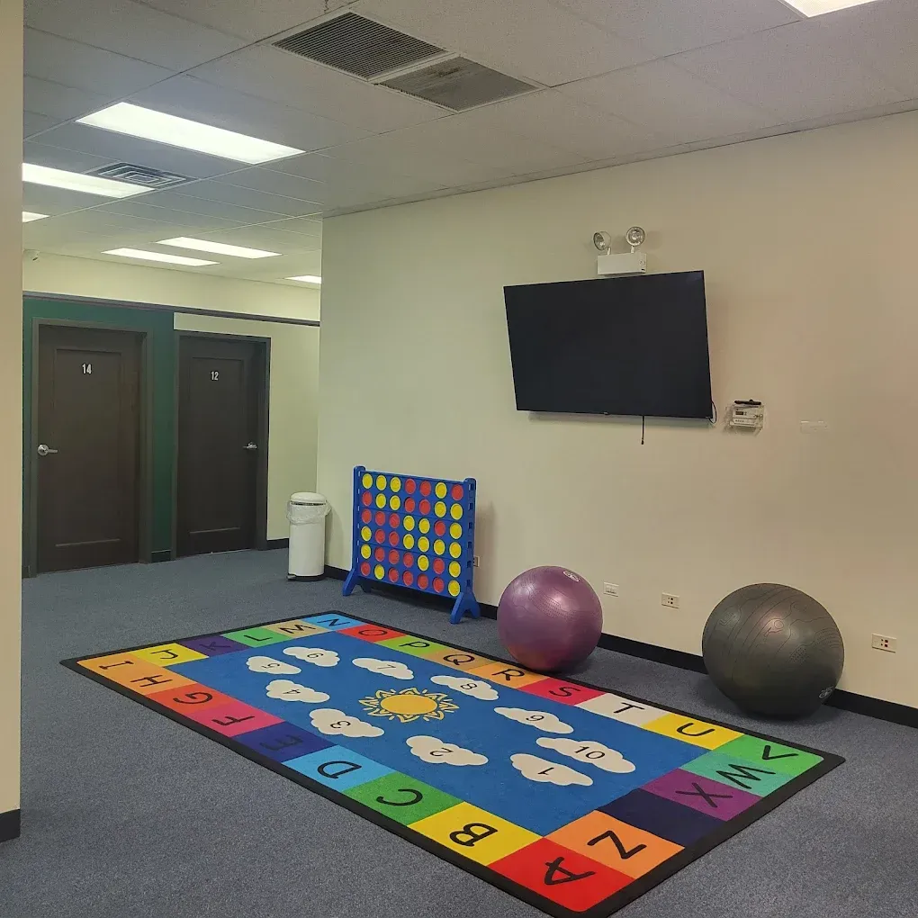 Bright playroom with colorful alphabet rug, exercise balls, and wall-mounted TV.