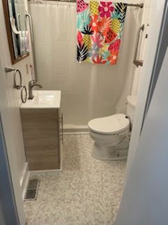 A bathroom with a toilet , sink , mirror and shower curtain.