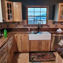 A kitchen with wooden cabinets , stainless steel appliances , a sink and a window.