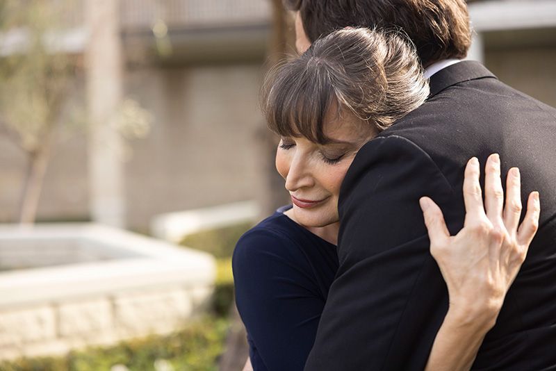 A man in a suit is hugging a woman in a blue dress.