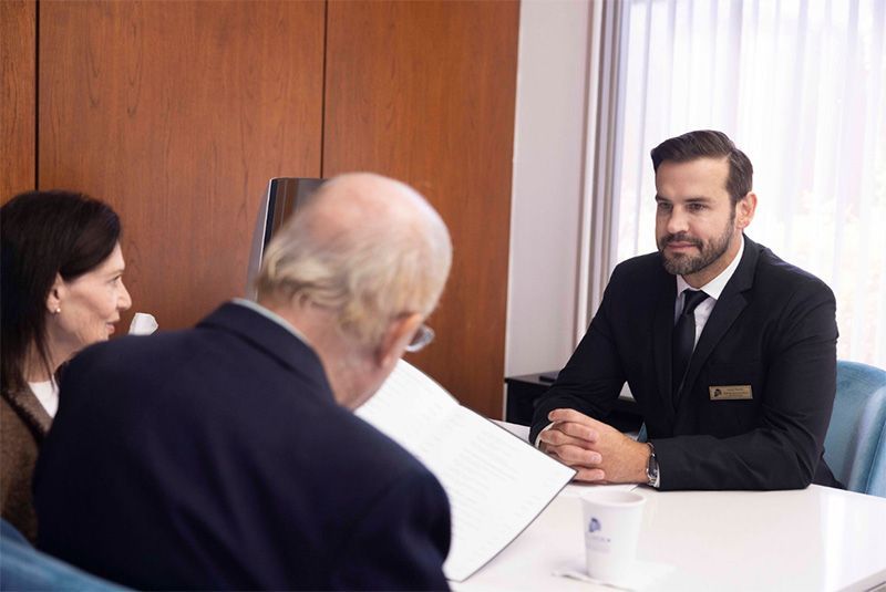 A man in a suit and tie is sitting at a table with two other people.