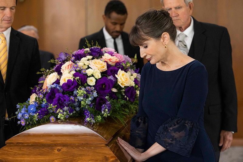 A woman has her hand on coffin with flowers at Hillside Memorial Park and Mortuary in Los Angeles, CA