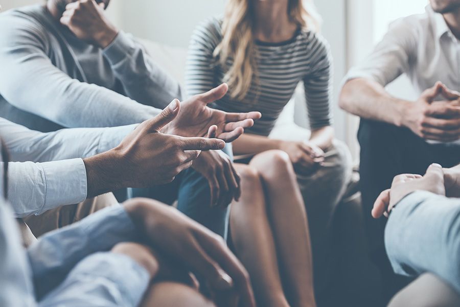 A group of people are sitting in a circle talking to each other.