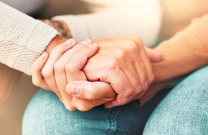 A man and a woman are holding hands while sitting on a couch.