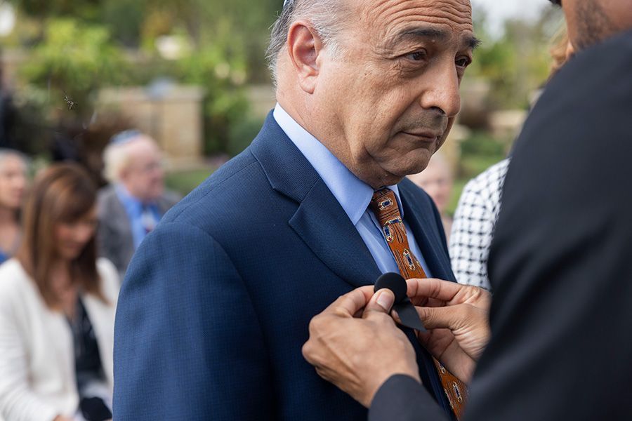 man getting black ribbon pinned on at jewish funeral service