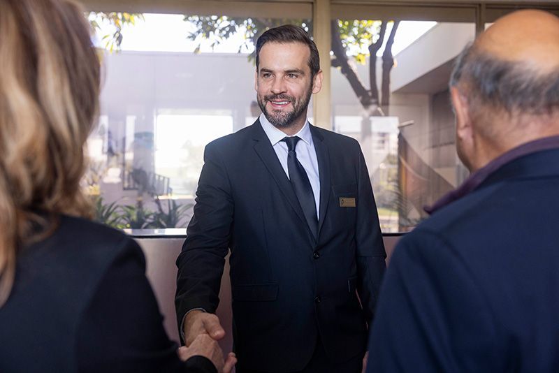 A man in a suit and tie is shaking hands with two people.