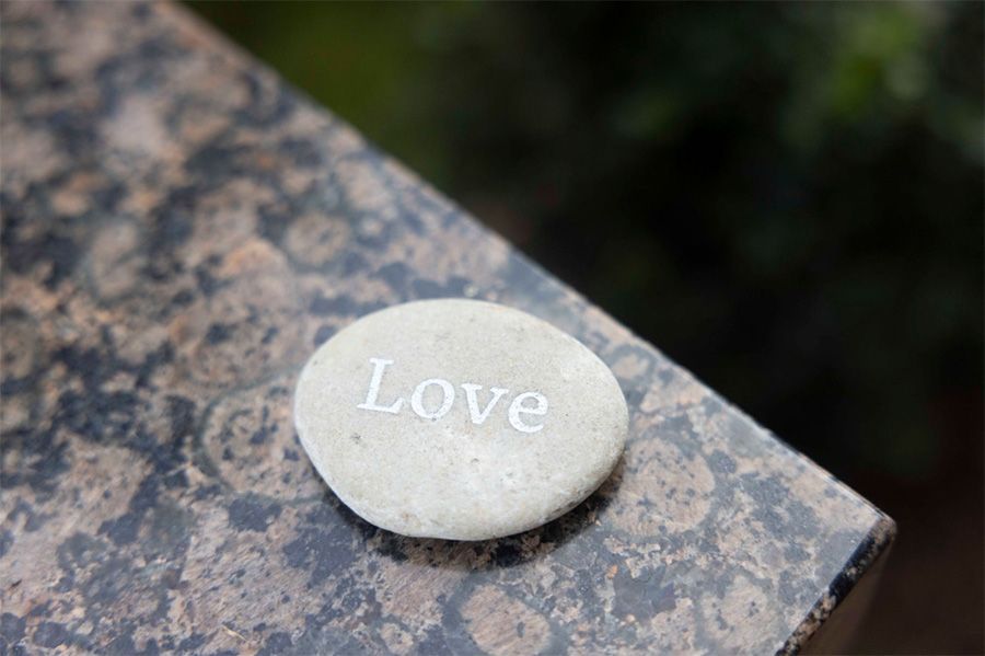 A rock with the word love written on it is sitting on a marble surface.