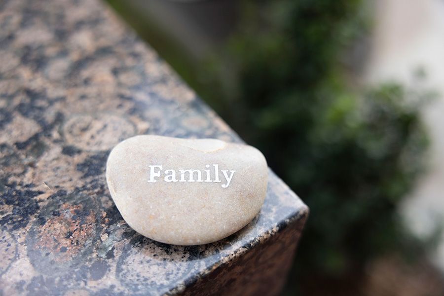 A rock with the word family written on it is sitting on a granite surface.