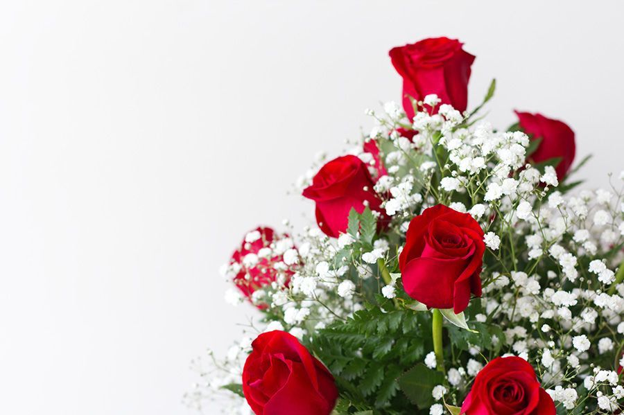 A bouquet of red roses and baby 's breath on a white background.