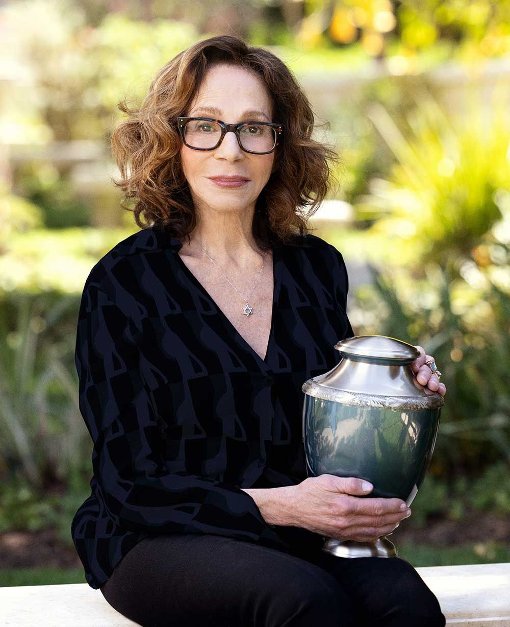 Woman with Star of David necklace holding a cremation urn.