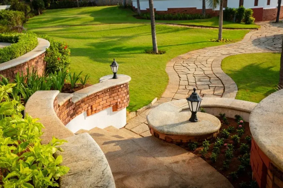 Curved stone garden path with steps, lanterns, and green lawn in a landscaped yard