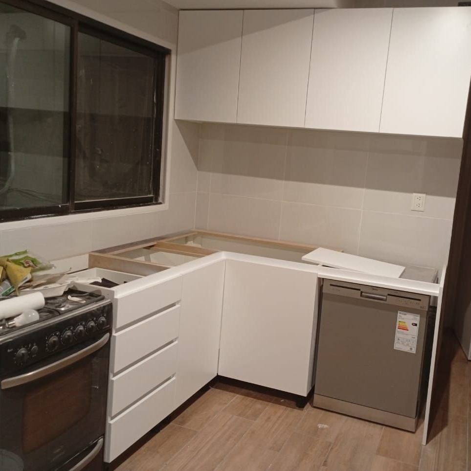 Muebles de cocina blancos con lavavajillas y estufa integrados. Renovación parcialmente terminada.
