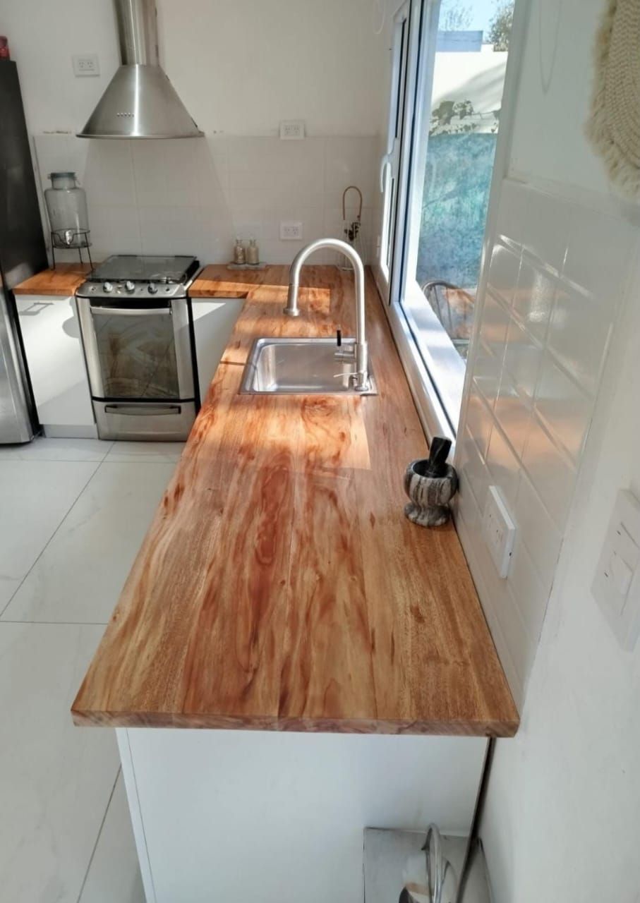 Encimera de madera con fregadero y grifo de acero inoxidable en una cocina luminosa.