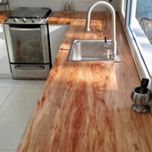Mesa de comedor de madera con borde natural y patas de metal negro en forma de X en un entorno de taller.