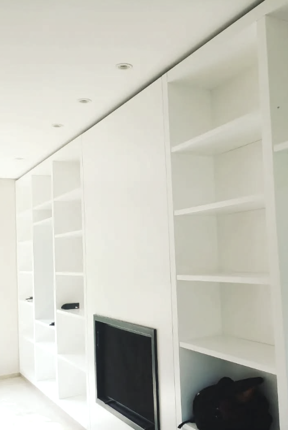 Estantes empotrados blancos que flanquean un televisor de pared. Iluminación empotrada.