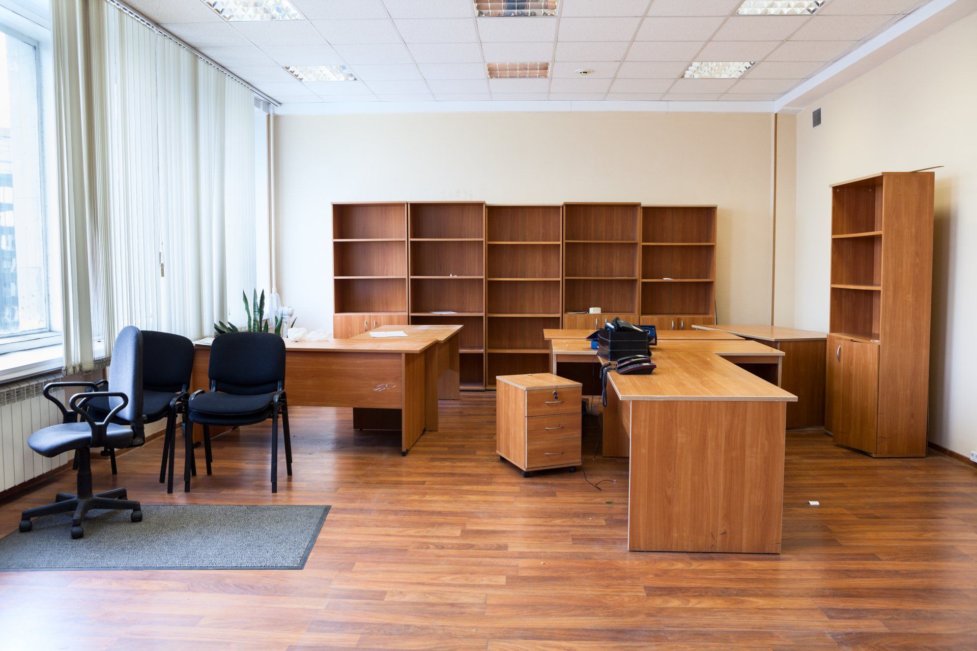 Un bureau vide avec des bureaux en bois, des chaises et des étagères.